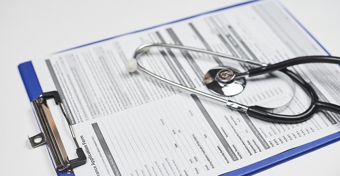 High angle closeup shot of a stethoscope on a travel insurance application document